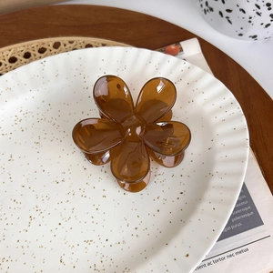 Detail shot of a translucent amber resin flower hair claw clip on a white decorative tray