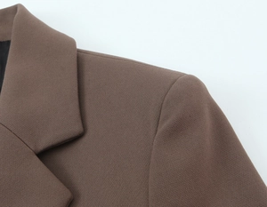 Détail d'un blazer marron à double boutonnage montrant la texture du tissu et l'épaule