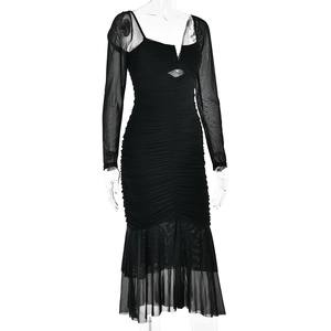 Detailed view of black slim-fit dress with mesh patchwork sleeves and fishtail hem