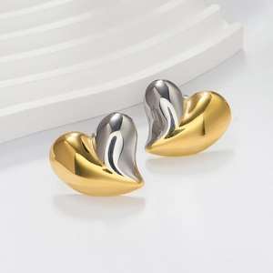 Close-up of 18K gold and silver two-tone heart stud earrings on a white wavy prop
