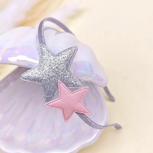 Detail of grey sequin star headband resting on a pearlescent white shell accessory