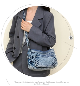 Detail of blue denim crossbody bag with multiple zip pockets and adjustable strap on model