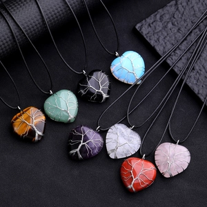 Multiple heart-shaped gemstone necklaces with Tree of Life wire wrapping on dark background