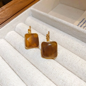 Gros plan de boucles d'oreilles vintage en résine ambrée dorée sur support en velours