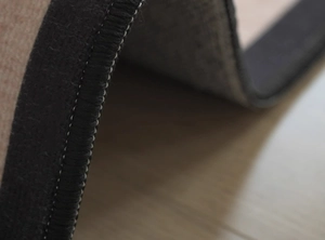 Macro detail of high-quality vintage rug showing black fabric edge and white stitching