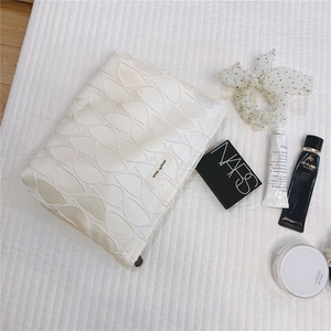 Detailed view of 3D leaf quilting texture and simple wish brand tag on white pouch