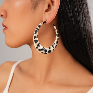 Close-up of a model wearing large black and white leopard print resin hoop earrings