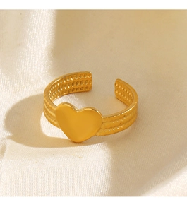 Détail d'une bague coeur dorée sur tissu blanc doux avec éclairage chaleureux