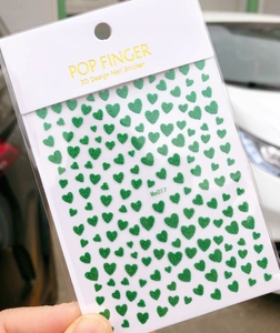 Detail shot of green glitter heart 3D nail stickers on Me017 packaging sheet