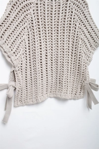 Detail of chunky knit texture and side ribbon tie design on beige sweater vest