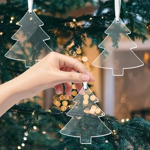 Transparent acrylic Christmas tree ornaments hanging with white silk ribbons and festive lights