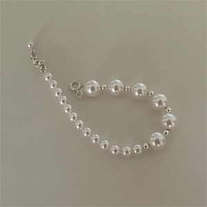 Detailed view of white pearl bracelet with gradient bead sizes and silver spring clasp