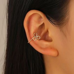 Gros plan d'un ear cuff doré à trois anneaux de style trèfle minimaliste sur l'oreille