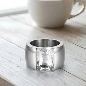 Macro shot of silver polished wide band ring featuring a clear emerald cut zircon stone