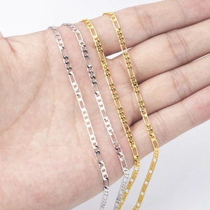 Macro shot of gold and silver 2.5mm Figaro chain links showing texture and metallic luster