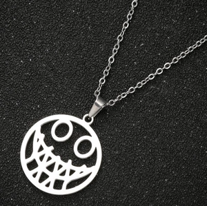 Macro shot of silver-toned skeleton face pendant on black textured background