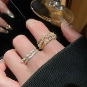 Close-up of stacked gold rings with zircon inlay and pearls in French luxury style
