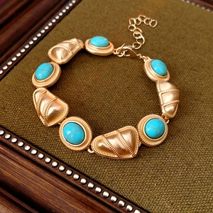 Détail d'un bracelet vintage doré avec pierre turquoise sur plateau de velours