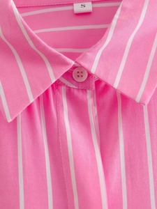 Détail du col d'une chemise à rayures roses et blanches avec boutons et coutures