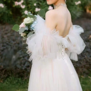 Detail of bridal white dress featuring voluminous puff sleeves and lace-up back design