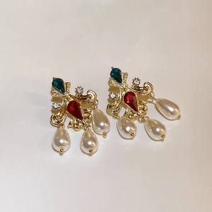 Vintage gold earrings with red teardrop stones and pearl tassels on a white background