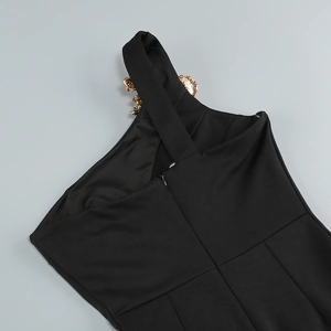 Détail d'une robe noire à épaule dénudée avec fermoir floral doré et fermeture éclair