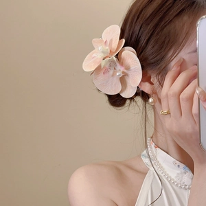 Detailed view of pink orchid hair clip with central pearl accents on elegant hairstyle
