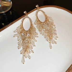 Close-up of golden tassel earrings with sparkling crystals and rhinestones in a tray