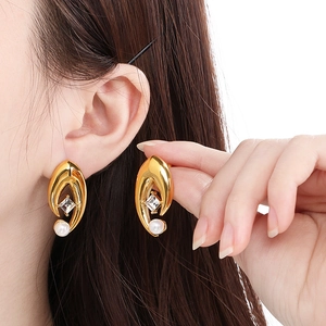 Gros plan de boucles d'oreilles œil grec dorées avec perles et cristaux sur modèle