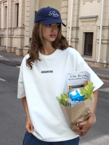 Dettaglio di una T-shirt bianca oversize in cotone con cappellino ricamato blu scuro