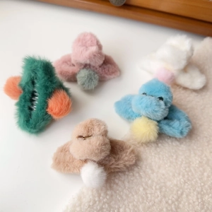 Close-up of five colorful plush hair claws with faux rabbit fur and contrast pom-poms