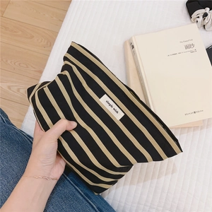 Close-up of a striped cotton canvas makeup bag with a simple wish woven label