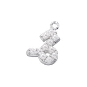 Macro shot of silver letter S pendant inlaid with lustrous white pearls for jewelry