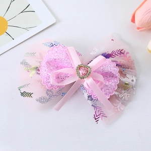 Close-up of pink tulle sequin bow hair clip with heart rhinestone and flower decor