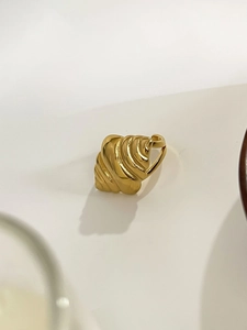 Detailed macro view of gold-plated spiral shell-textured stainless steel ear cuff