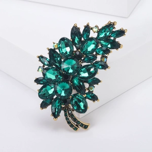 Detailed macro view of vintage gold brooch featuring emerald green marquise crystals