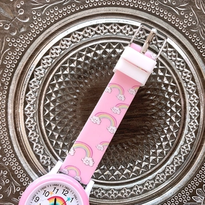 Detail showing pink silicone strap with rainbow and cloud print on children watch