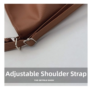 Detail of adjustable brown pebbled leather shoulder strap with silver metal buckle