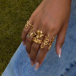 Golden flower butterfly stackable ring set worn by model against a natural background