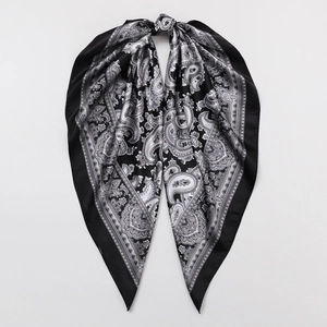 Detailed view of the paisley pattern on a silky black and grey square scarf