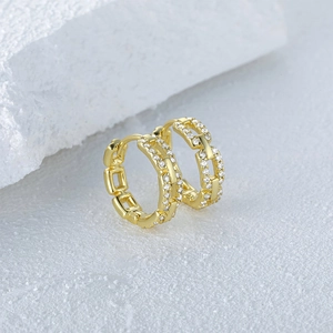 Macro detail of gold chain-link hoop earring with sparkling white cubic zirconia stones