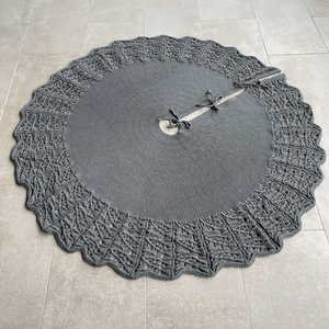 Detailed view of dark grey knitted Christmas tree skirt with hollow wave edge and ties