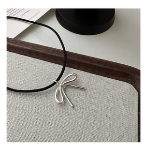 Close-up of S925 sterling silver bow pendant on a black cord with engraved hallmark