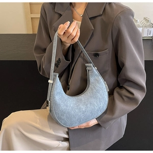 Blue crescent hobo bag with matte texture and silver hardware shown held by a model