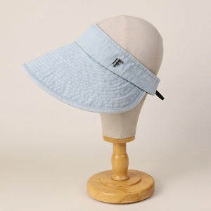 Close-up of light blue denim sun hat with metal logo and wide brim for UV protection