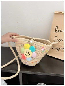 Detail of straw woven crossbody bag featuring a plush colorful smiley flower and pearls