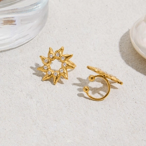 Détail de boucles d'oreilles soleil dorées 18K avec cristaux brillants sur fond texturé