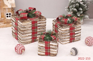 Detail view of woven rattan Christmas gift boxes with red plaid ribbons and pine cones
