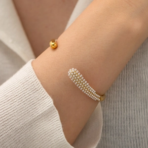 Close-up of golden 18K stainless steel open cuff bracelet with white pearl cluster detail