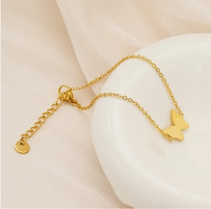 Macro detail of gold butterfly bracelet showing S.Steel engraving and extension chain
